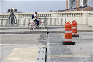 A bicycle passes where crews from City of Toledo Streets, Bridges & Harbor began to fix four expansion joints on the Martin Luther King, Jr. Bridge in Toledo. The fixed is forefront left. What needs fixed is back left (crumbling concrete).