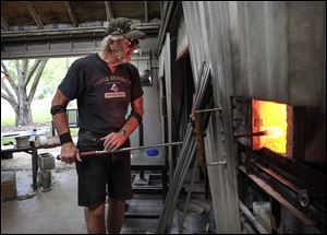 Randy Kuntz heats glass as he works to make a glass shorebird at the Artist Village of the Toledo Botanical Garden.