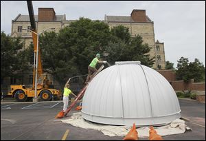 Lucy Ruggiero holds the hose to the paint sprayer as Jeremy Baum paints the dome of the Brooks Observatory, which was removed from the top of McMaster Hall on the University of Toledo campus. 