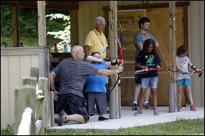 Hunter Roberts, 13, of Perrysburg, prepares to shoot a bow and arrow with the help of volunteer Bill Kreeger.