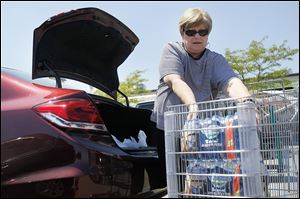 Lynn Duty of Toledo puts packages of bottled water in her car on Tuesday at The Anderson's on Talmadge Road in Toledo, Ohio. The water safety level is at ‘watch.’