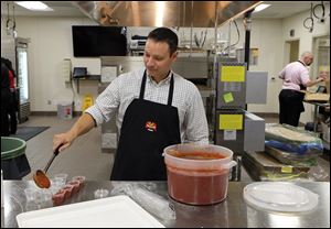 Robert Tankoos of Charlotte ladles marinara sauce into small cups to accompany cheesy bread orders. Mr. Tankoos, who is originally from Toledo, and the other franchisees put their skills to the test at Marco’s Pizza corporate office.