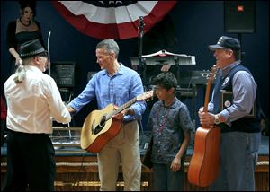Ken Leslie, left, presents Steve Baugh, president and CEO of Jordan Reses Supply Co., second from left, and Lee Armstrong of the Lucas County Veterans Services Commission, right, with autographed John Mellencamp guitars.