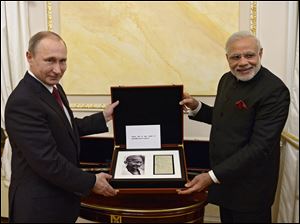 Russian President Vladimir Putin, left, and Indian Prime Minister Narendra Modi pose for a photo while exchanging official gifts during their meeting in the Kremlin in Moscow Wednesday.