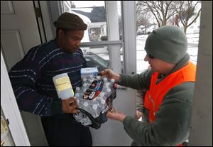 Louis Singleton receives water filters, bottled water and a test kit from Michigan National Guard Specialist Joe Weaver as clean water supplies were distributed to residents in 2016 in Flint, Mich. 