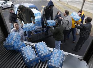 Village Church member Jackie Quinones, bottom left, helps collect bottled water for Flint at the Toledo Police Patrolman's Association parking lot in Toledo in January.