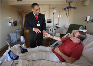 Rev. Lee Williams, chaplain at St. Luke’s Hospital in Maumee, prays with Jim Phister in his hospital room after a knee replacement.