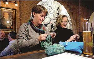 Carol Cierniak, left, and Laura Frailey knit and drink beer at the Black Cloister Brewing Co. bar in downtown Toledo.