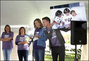 Above, Kyle Rubini, second from right, smiles as her brother Ian holds up a photo of them with their sister Claire during the annual Claire’s Day at the Maumee branch of the Toledo-Lucas County Public Library. The 15th annual event aimed at inspiring children to read was Saturday. 