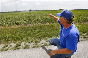 Mark Drewes watches Ben Brickner, an employee, spray soybeans in a field in Custar. ‘I don’t want to sound like a complainer,’ Mr. Drewes said. ‘But we’ve been through a pretty chal­leng­ing year this year af­ter what hap­pened last year.’ 