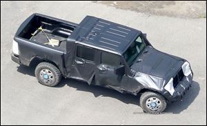 This is a spy photo of a masked Jeep Wrangler pickup truck, shot in July, 2016.