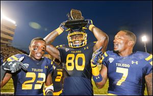 Toledo's Michael Roberts holds the Battle of I-75 trophy as he and teammates DeJuan Rogers and Delando Johnson celebrate the Rockets win over Bowling Green at the Glass Bowl last season. Toledo has won the last 7 games in the I-75 Rivalry series.