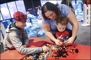 Alex, 16, left, plays Legos with her brother Ian, 3, and stepmother Laura Henricks of Adrian at the Imagination Station. 