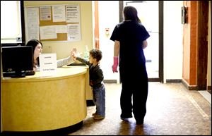 Employee Taylor Tye, left, gives little resident Preston Gould, 2, a high five, while his mother, Amanda Workman, watches after lunch in Family House.