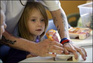 Brian Roberts helps his daughter Jazmine Roberts, 7, of Toledo, open packages for her during lunch at Family House.