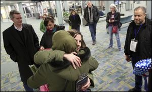 Kathy Savage of Toledo, center, hugs refugee Ghada, who declined to give her last name, shortly after Ghada, her husband Khaled, right, and their eldest son, Fadi, not pictured, arrived at Toledo Express Airport.
