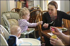 Tiffanie Howell feeds her 15-month-old daughter Kensingtyn at the Aurora Project Inc. house in Toledo. Aurora Project gets $76,296 in federal block grant funds.