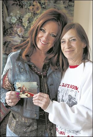 Sisters Linda Burns, 66, left, of Discovery Bay, Calif., and Evamaria Kinner, 61, of Decaturville, Tenn., hold a 1983 photograph showing their father Bronis Yakovanis fishing in Florida.
