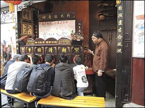 Customers peer through a bioscope in Shanghai to see a show of still pictures with commentary from the operator.