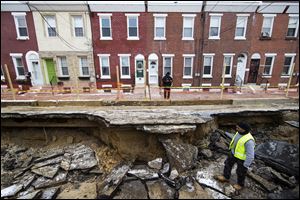 Workers inspect a sinkhole in Philadelphia. The Philadelphia Water Department said a water main break caused the sinkhole to open up on the street. 