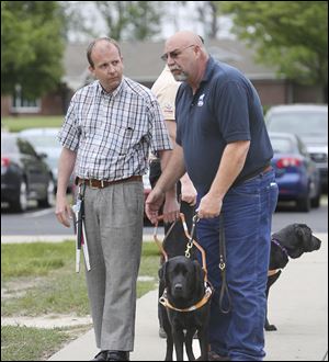 Christopher Hall, left, learns how to hold the harness of Robin, a Labrador retriever, from Greg Levick, from the Guide Dog Foundation.