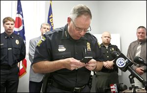 Toledo police Chief George Kral uses a cell phone to demonstrate the danger of texting while driving during a news conference Wednesday at the Safety Building.