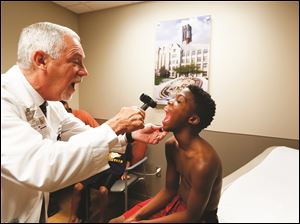 Dr. David Weldy examines Jordan, who was required to pass a sports physical before he can play youth football.