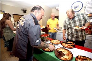 Steve Pahle, left, Gary Jones, center, and Tom Dennis, dig in as pizza and other Italian dishes were offered to friends and family in celebration for Inky’s Italian Foods still being in business after opening  its doors in 1957.