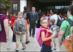 Principal Shaun Mitchell, center, greets students at the front door Thursday morning on the first day of classes at DeVeaux Elementary School in Toledo.