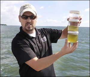 Chris Winslow, Ohio Sea Grant and Ohio State University Stone Lab director, holds jars of raw Lake Erie water, showing the telltale green of algae.