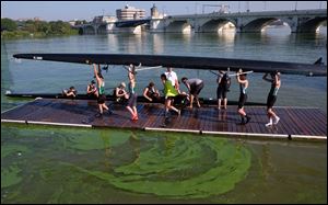 A team prepares to enter the algae-covered Maumee River during the ProMedica Frogtown Regatta at International Park in Toledo Saturday.