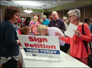 League of Women Voters representatives Starr Wlodarski, left, and Josette McCarthy, both of Perrysburg, speaking with forum attendees Kathleen Gibson, of Perrysburg Township (bending over desk toward McCarthy), Rick Hoff and his wife Terry Hoff, of Perrysburg about a petition. The League's petition is 
