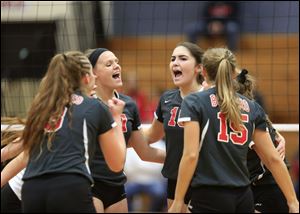 Bedford players celebrate after winning a point during a Michigan Class A regional volleyball final against Livonia Churchill at Monroe High School.