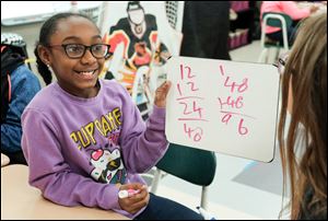 Anjali Campbell holds up the correct answer to teammate Sydney Genot in response to a math problem at Wayne Trail Elementary School in Maumee, Ohio on Wednesday, Nov. 15.