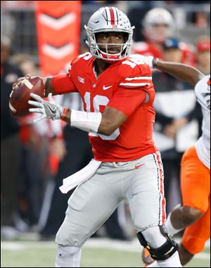Ohio State quarterback J.T. Barrett drops back to pass Saturday against Illinois. Barrett, playing in his final game in Columbus, threw two touchdown passes and ran for another in the Buckeyes' victory.