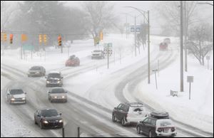 Traffic moves in cold and snowy conditions Jan. 7, 2014 along U.S. 31 near West Grand Traverse Bay in Traverse City, Mich. The state should reconsider its onerous fees that have left roughly 317,000 people without licenses.