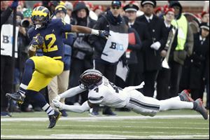Michigan's Chris Evans dodges Ohio State's Jordan Fuller on a  run during last year's rivalry game.