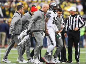 Ohio State's J.T. Barrett leaves the game after after being injured in the third quarter of Saturday's 31-20 win over Michigan.