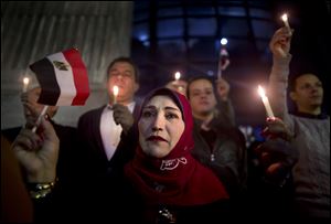People take part during a candlelight vigil as they hold national flag for victims of a Friday mosque attack at the Journalists Syndicate, in Cairo, Egypt.