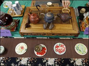 Li Yan, originally from China, left, brought a portion of her traditional tea service to share during a Halloween-themed potluck October 31 at the Sylvania Schools Administrative Offices.