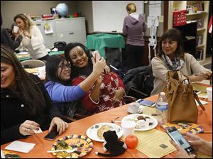 Tram Vo, originally from Vietnam, center left, snaps a selfie with Tigist Mekonnen, originally from Ethiopia, center right, during a Halloween-themed potluck October 31 at the Sylvania Schools Administrative Offices.