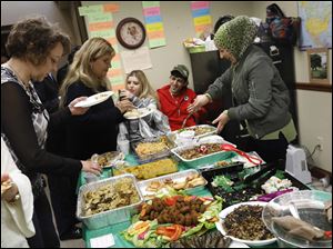 Itaf Moussa, right, laughed as she dished up food during a Halloween-themed potluck October 31 at the Sylvania Schools Administrative Offices. 