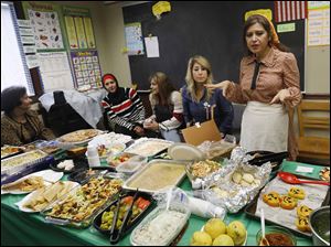 Instructor Najwa Badawi, right, encourages her students to take food home with them at the end of a Halloween-themed potluck October 31 at the Sylvania Schools Administrative Offices.