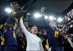 From left, defensive back Trevon Mathis, Toledo head coach Jason Candle, and quarterback Logan Woodside celebrate beating Akron at Ford Field as UT won its first MAC title since 2004.