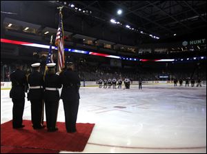 Players stand facing the flag during the national anthem during the Battle of the Badges Toledo Police Department vs. Toledo Fire Department hockey game at the Huntington Center in Toledo on Saturday, December 2.