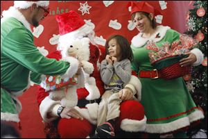 Isabella Lerma, 4, center, cheers as she receives her Christmas present from Santa at the Toledo Public Schools Head Start program.