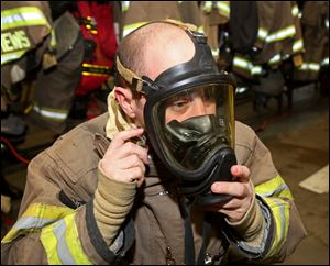 Pvt. Erin Martens, with the Toledo Fire Department, demonstrates the steps in putting on his turnout gear at Fire Station 5 in Toledo.