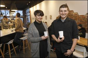 Micah Inak, 17, of Lakewood High School, left, and Ben Carr, 17, of Bowsher High School, winners of the Downtown Toledo Coffee Cup Award, stand with coffee cups displaying their art Thursday, December 21 at Claro Coffee Bar. The award is one part of the Ninth Congressional District Invitational Art Competition, presented by The Arts Commission and U.S. Rep. Marcy Kaptur (D., Toledo) since 1983. The students' artwork will appear on coffee cups around Toledo. 
