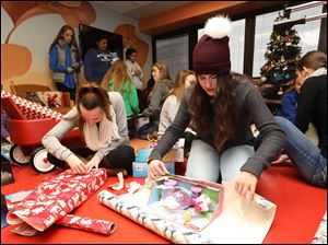 Lake High School juniors Chloe Umbaugh, center, and Ally Goetz, right, wrap presents for a toy drive at ProMedica Toledo Children's Hospital.