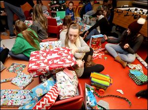 Lake High School's Chloe Umbaugh places a wrapped present in a wagon as part of a toy drive at ProMedica Toledo Children's Hospital.